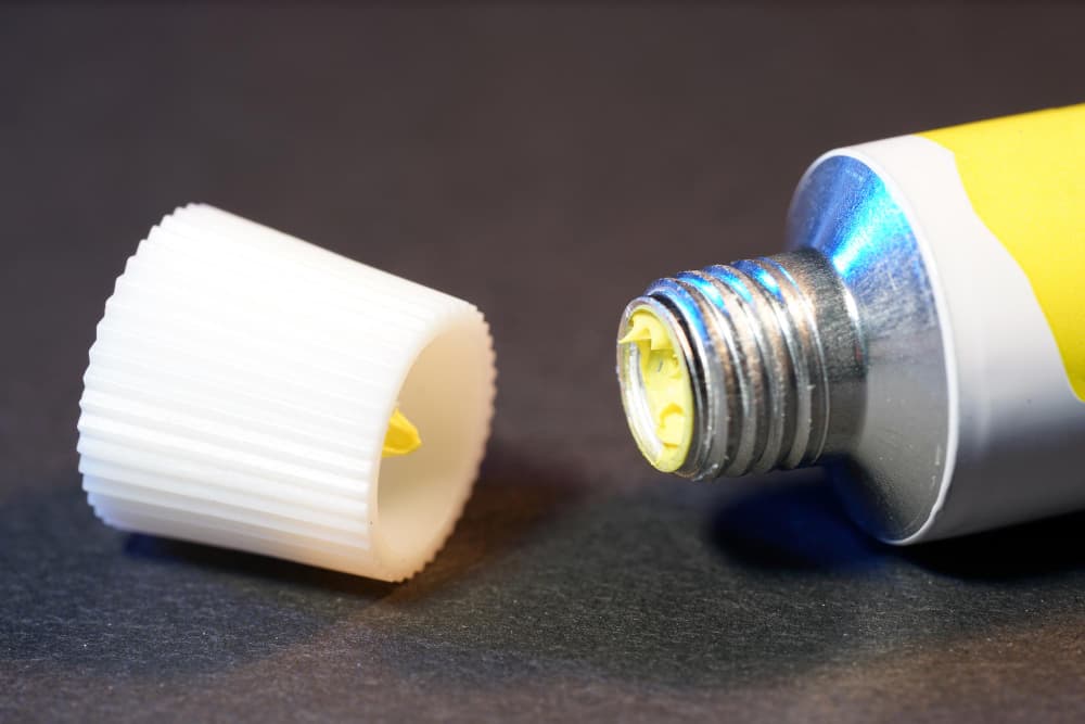 Ointment Tube and Cap – Types of Ointment Bases Guide 2025 | Pharma Manufacturing Yellow ointment tube with white screw cap on dark background, representing pharmaceutical ointment packaging and formulation