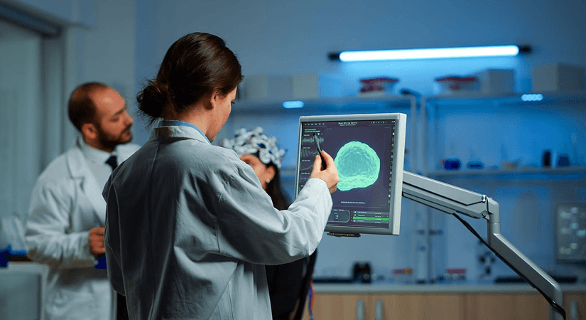 Schrodinger vs Insilico Medicine | AI Oncology Drug Discovery Researcher analyzing AI-generated molecular brain scan on monitor in a drug discovery lab with colleagues in background
