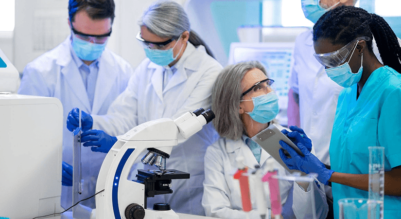 AI Biotech Commercialization | From Lab Research To Pharma Revenue Diverse biotech research team examining samples under a microscope in a modern lab, reviewing data on a tablet